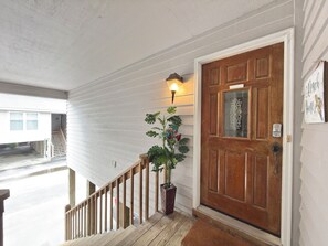 A wooden staircase leading to a front door with a potted plant beside it.