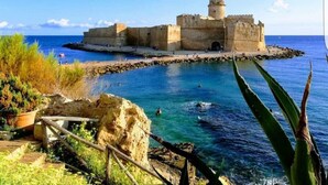 A coastal fortification with a clear view of the sea and a rocky shoreline.