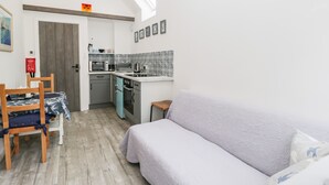 A compact living space with a kitchenette, a dining area with a table and chairs, and a sofa. - Little Crabapple (Swanage)