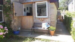 A wooden house with a wooden door, a bench, and a sign reading "Little Crabapple". - Little Crabapple (Swanage)