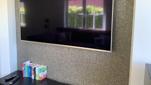 Ein Flachbildfernseher an einer strukturierten Wand, im Hintergrund ein Fenster.