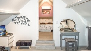 A bedroom with a bed, a bedside table, a bench, and a wall-mounted shelf.