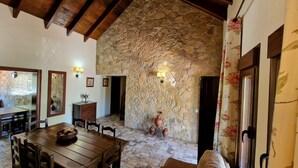 A dining area with a stone wall, wooden ceiling beams, and a table with chairs. - Quiet Villa with heated swimming pool, barbecue and views. (Alhaurín el Grande)