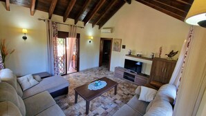 A living room with a sofa set, a coffee table, and a TV. There are curtains, a fireplace, and a ceiling with exposed beams. - Quiet Villa with heated swimming pool, barbecue and views. (Alhaurín el Grande)