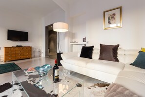 A modern living room with a white sofa, a glass coffee table, a television, and a lamp. - Centrally located modern 2 Bed apartment in Cannes with aircon and modern design - 696 (Cannes)