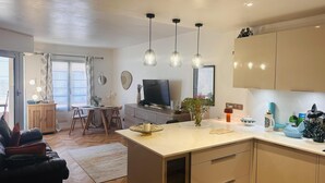 A modern kitchen with a central island, pendant lights, and a dining area with a table and chairs.