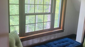 A room with a large arched window, a blue cushioned bench, and a glass table.