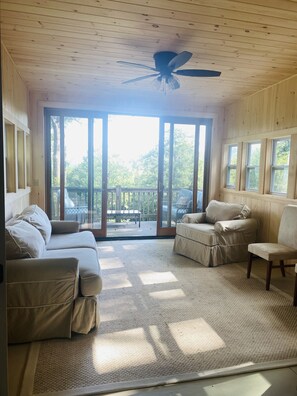 Una habitación amplia con un gran ventanal corredera que da a una terraza exterior.