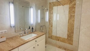 A modern bathroom with a large mirror, a sink, and a shower area.