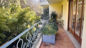 A balcony with a metal railing, potted plants, and a tiled floor.