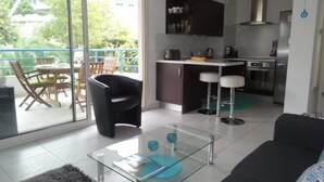 A modern kitchen with a dining area, a sofa, and a glass coffee table. - Modern 1-Bed Apt near Cannes Seafront & Pool - 1753 (Cannes)