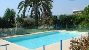 A swimming pool surrounded by palm trees and a fence. - Modern 1-Bed Apt near Cannes Seafront & Pool - 1753 (Cannes)