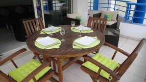 A round wooden table with green cushions, set for four people. - Modern 1-Bed Apt near Cannes Seafront & Pool - 1753 (Cannes)