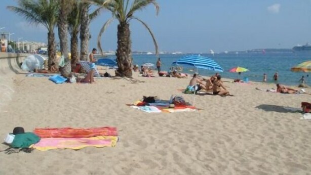 A beach with palm trees, umbrellas, and people relaxing. - Modern 1-Bed Apt near Cannes Seafront & Pool - 1753 (Cannes)