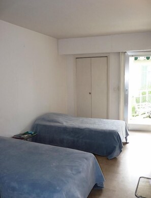 A room with two single beds, a white wardrobe, and a sliding glass door leading to an outdoor area. - Three bedroom, two bathroom apartment in Cannes with large terrace - 880 (Cannes)