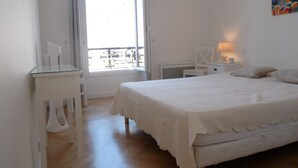 Ein Schlafzimmer mit Bett, Nachttisch, Stuhl, Fenster und einem Bild an der Wand.
