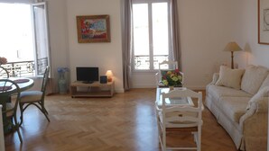 Ein Wohnzimmer mit Sofa, Fernseher, Lampe und einem Gemälde an der Wand.