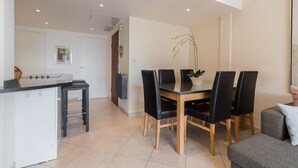 A modern kitchen with a dining area, featuring a black and white color scheme, a dining table with chairs, and a potted plant. - Modern 3BR/3BA cannes apt walk to Palais - 2000 (Cannes)