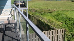 Una terraza con vista a un campo verde y al mar.