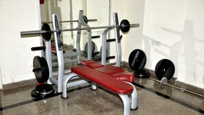 Une salle de sport équipée d’un banc de développé couché, de supports à poids et de divers poids libres.