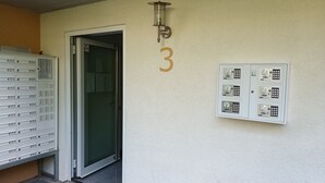 Een gebouwtoegang met brievenbus, deur en een intercom bevestigd aan de muur.