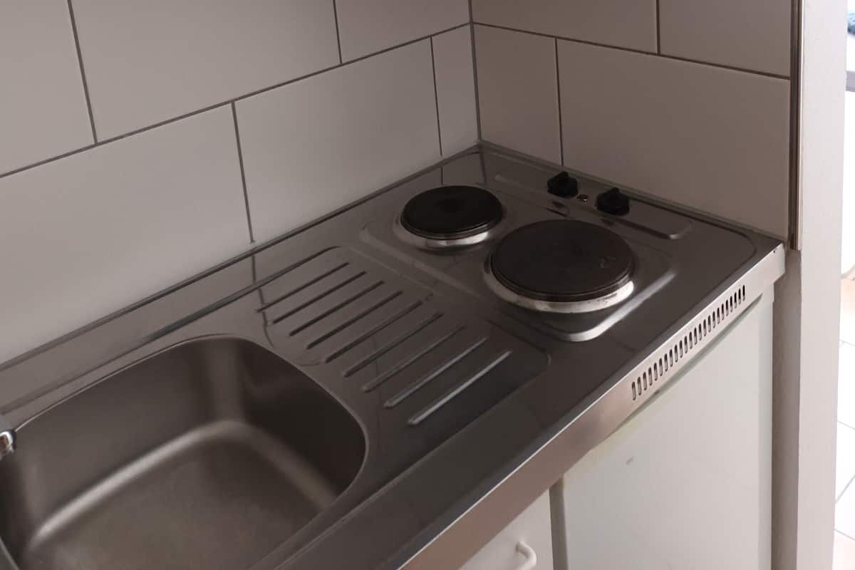 A kitchen with white cabinets, a stainless steel sink, and a double electric stove.