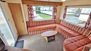 L’intérieur d’une caravane est aménagé avec un canapé incurvé, une petite table ronde et une porte donnant sur l’extérieur.