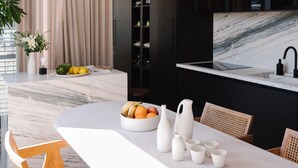 A modern kitchen with a marble countertop, a built-in oven, and a black backsplash. - Luxury Penthouse&Private Roof and Pool (Tel Aviv)