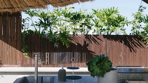 A concrete outdoor area with a thatched roof, a metal sink, a potted plant, and a wooden bench. - Luxury Penthouse&Private Roof and Pool (Tel Aviv)