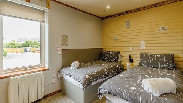 A bedroom with two beds, a window, and a radiator. - 1 bedroom accommodation in Haswell, Nr Durham (Haswell, Nr Durham)