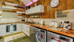 A modern kitchen with wooden accents, a built-in oven, a dishwasher, a coffee maker, and a clock on the wall. - 3 bedroom accommodation in Haswell, Nr Durham (Haswell, Nr Durham)