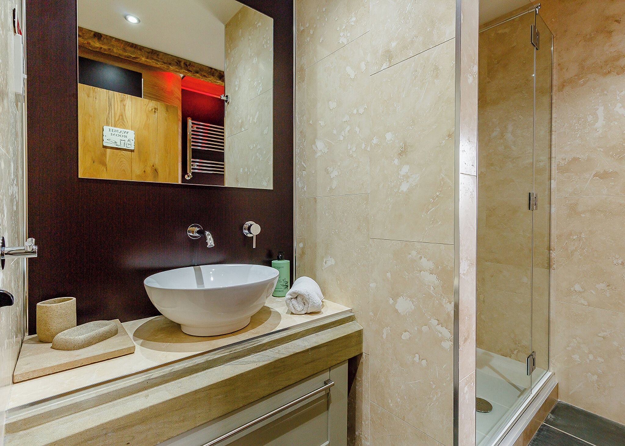 Une salle de bain avec un grand lavabo blanc, une douche en verre et un meuble-lavabo en bois.