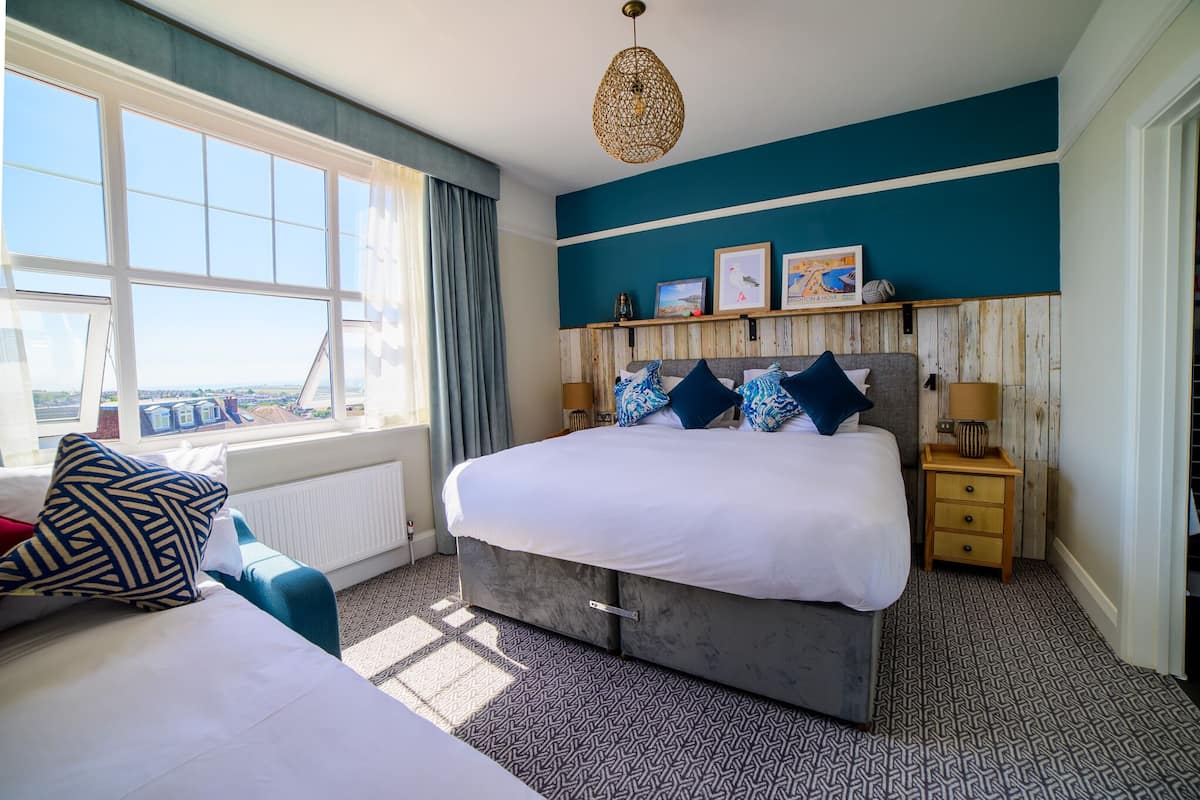 A bedroom with a large bed, a view of the city, and a wooden headboard.