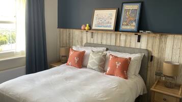 A hotel room with a large bed, wooden headboard, and two bedside tables. There are decorative pillows and a framed picture on the headboard.