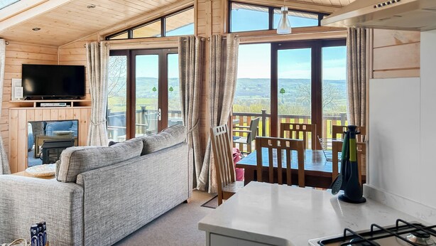 L’intérieur d’un chalet en bois comprend un canapé, un téléviseur, une table à manger, des chaises et un coin cuisine.