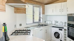 Une cuisine compacte équipée d’une cuisinière à gaz, d’un évier et d’un lave-linge encastré.