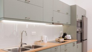 Une cuisine moderne avec des meubles de couleur vert clair, des appareils en acier inoxydable et un plan de travail en bois.