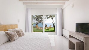 Une chambre dotée d’un grand lit, d’une télévision et offrant une vue sur un espace verdoyant avec des arbres et une étendue d’eau.
