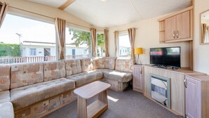 A caravan interior with a sofa, a television, and a small table.