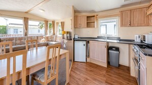A compact kitchen with wooden cabinets, a sink, a stove, and a small refrigerator.