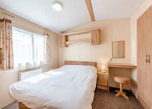 Ein Schlafzimmer mit Bett, Nachttisch, Lampe und Kleiderschrank.