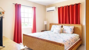 Ein Schlafzimmer mit Bett, Vorhängen, einer Klimaanlage und einem Fenster.