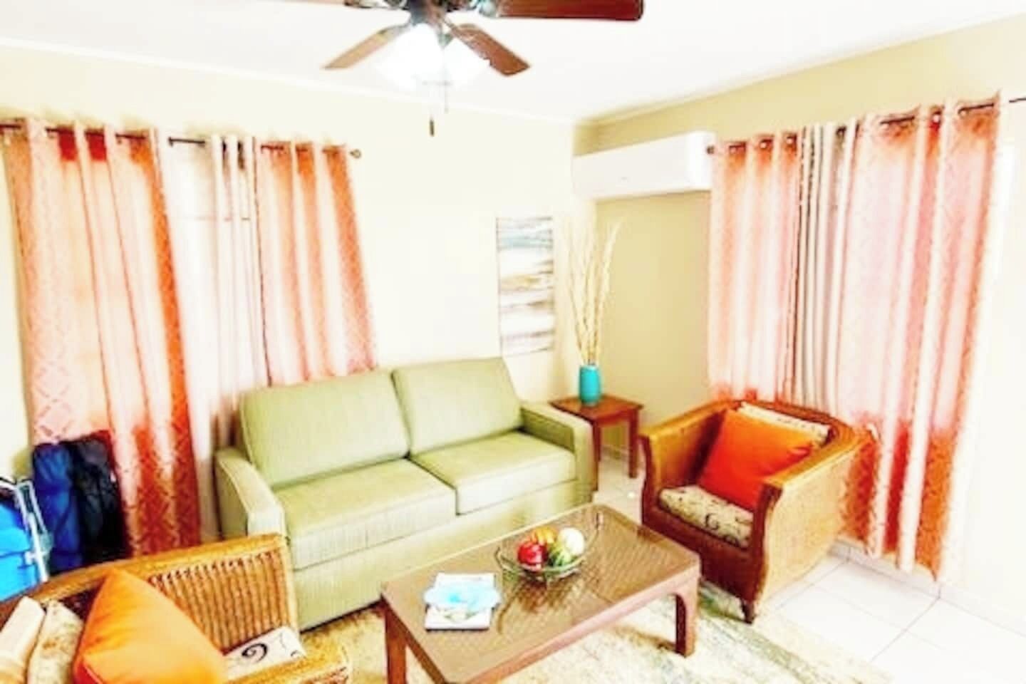 Ein Wohnzimmer mit einer Couch, einem Sessel, einem Couchtisch und Vorhängen.