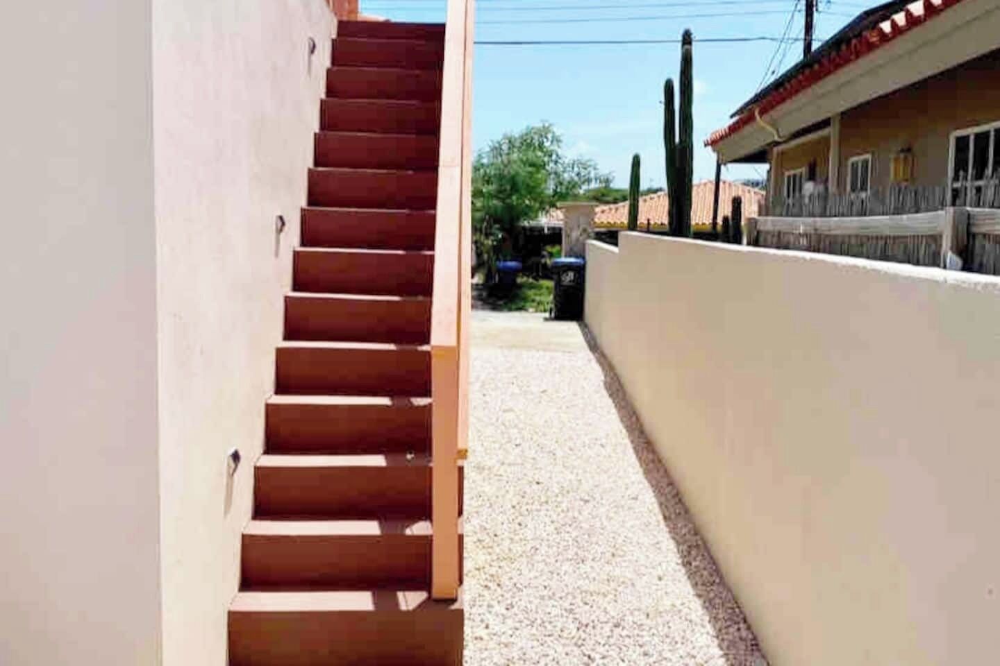 Una escalera que lleva a un edificio con fachada blanca y tejado rojo.