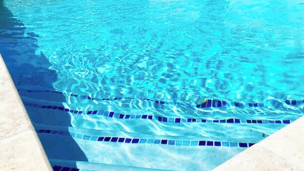 Ein Pool mit klarem Wasser und blauen Fliesen am Boden.