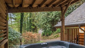 Een hottub onder een houten pergola, met uitzicht op een bos.