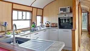 A compact kitchen with a sink, toaster, microwave, and oven. - Brunel Boutique Railway Carriage 3 (Dawlish Warren)