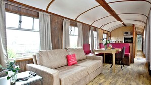 A cozy interior with a sofa, dining table, and kitchen area. - Brunel Boutique Railway Carriage 3 (Dawlish Warren)