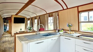 A compact kitchen with a sink, cabinets, and a window. - Brunel Boutique Railway Carriage 3 (Dawlish Warren)