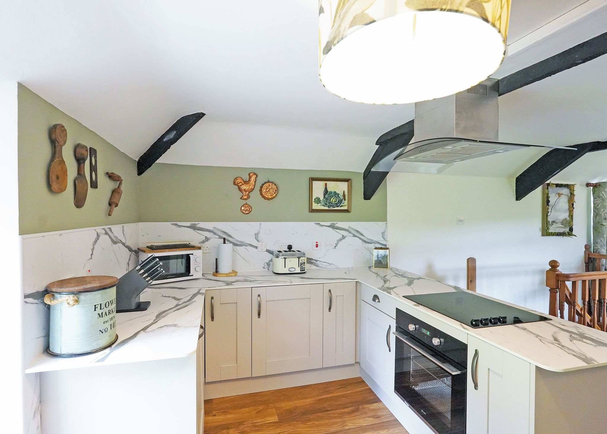A compact kitchen with white cabinets, a microwave, a toaster, and a stove.